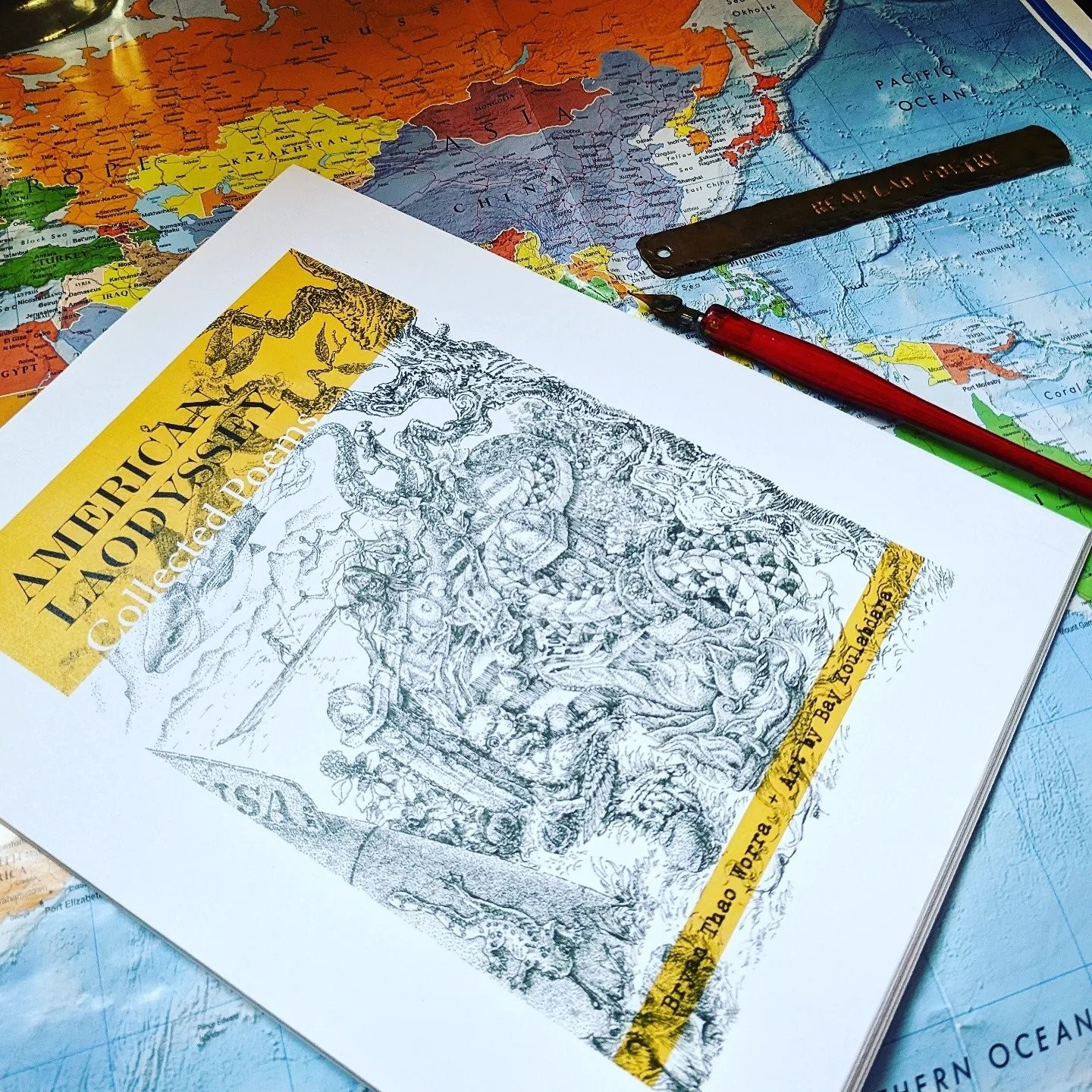 Proof of American Laodyssey: Collected Poems by Bryan Thao Worra with art by Bay Koulabdara, detailed ink cover art, on a world map with a dip pen.