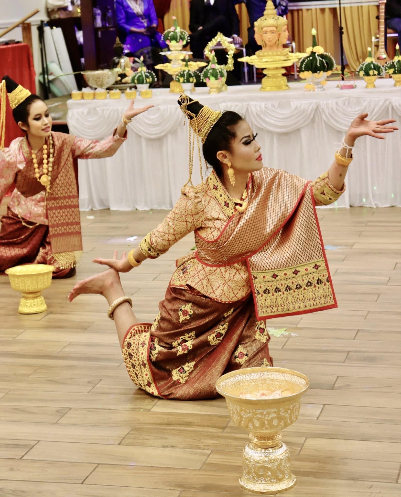 Lao classical dancers in gold-trimmed sinh and pointed crowns perform beside ornate gold offering bowls