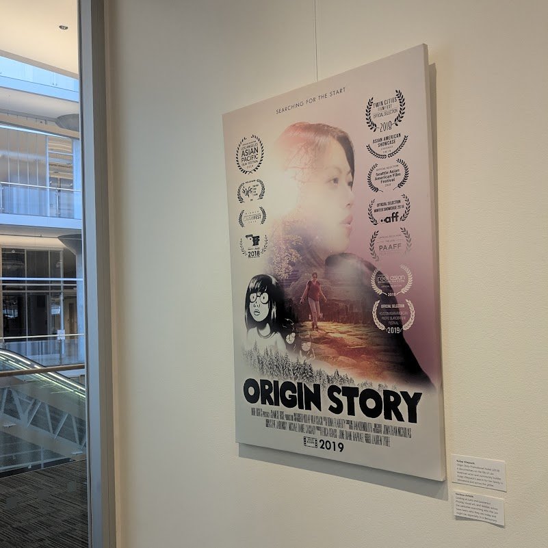Origin Story film poster with festival laurels hanging on a gallery wall