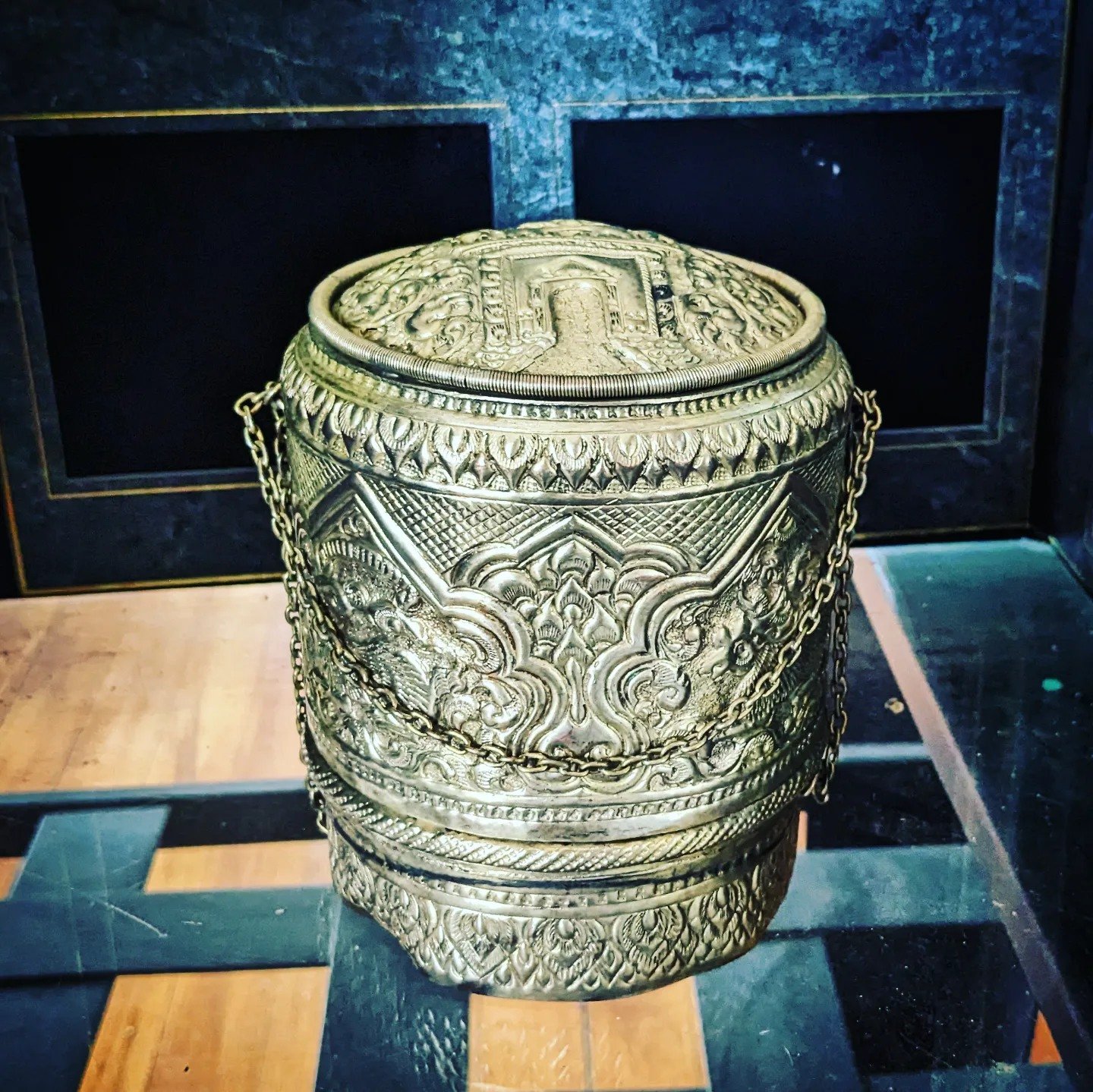 Ornate embossed silver lidded container with a chain handle, displayed in the Laomerica 50 exhibit