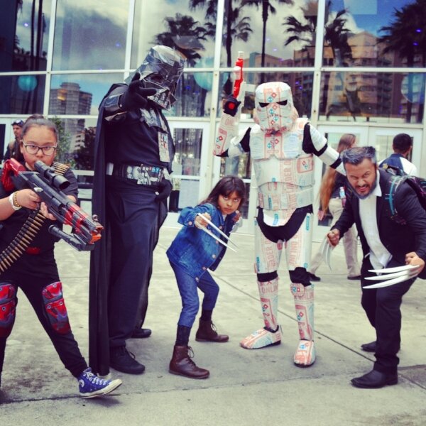 Cosplayers pose outside the expo: Darth Vader, a patterned Stormtrooper, and a child and man with Wolverine claws