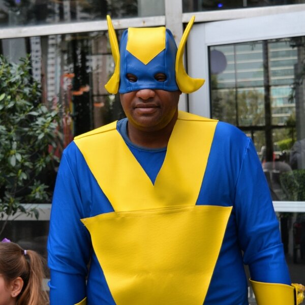 Man in a blue and yellow superhero costume with a horned mask