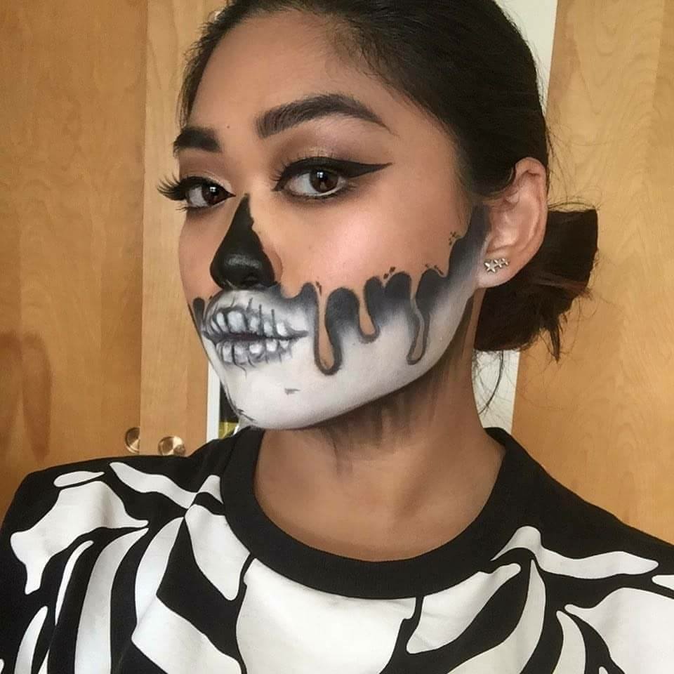 Young woman with half-face skeleton makeup and a skeleton-print sweater.