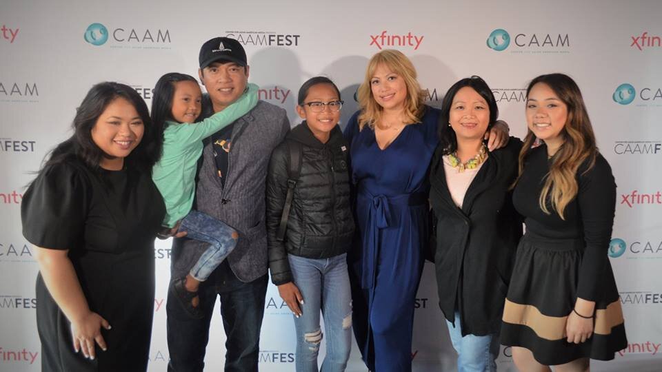 Group of adults and children posing in front of a CAAMFest step and repeat backdrop