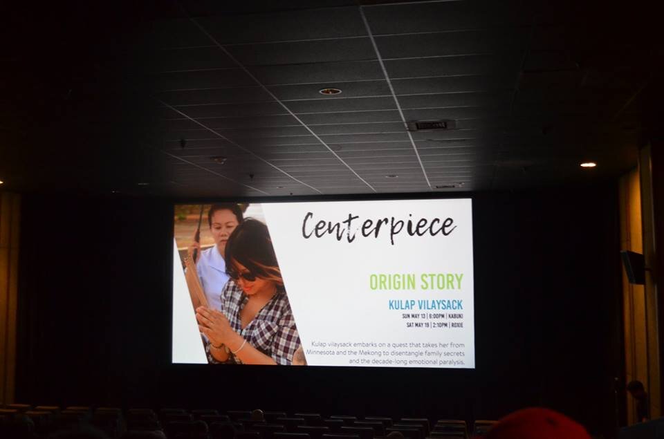 Movie theater screen showing the CAAMFest Centerpiece slide for Origin Story by Kulap Vilaysack