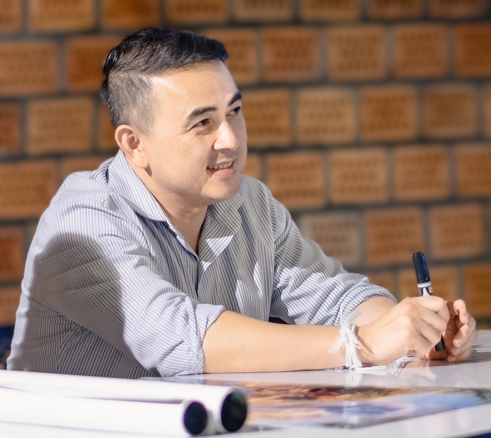 Steve Arounsack, director of Getting Lao'd, smiling at a table holding a marker