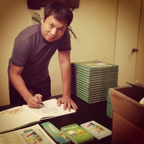Man signing a book at a table stacked with copies of A Sticky Mess