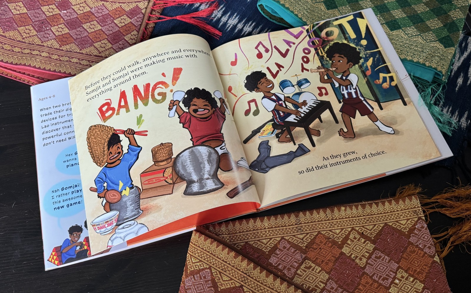Open children's book depicting children playing musical instruments and making music, with colorful illustrations and the word 'BANG!' on the page.