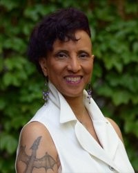 Portrait of Linda D. Addison smiling in front of green ivy