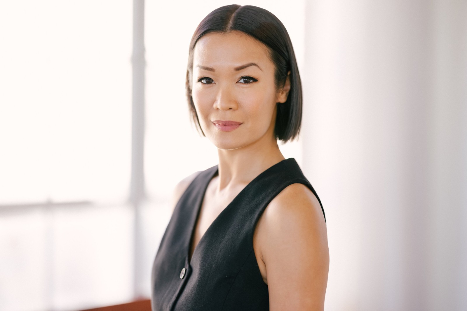 Sydney Viengluang in a black sleeveless vest, posing in a bright room