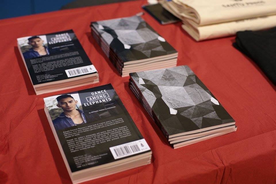 Copies of Dance Among Elephants by Krysada Panusith Phounsiri on a red table, back covers showing the author's photo